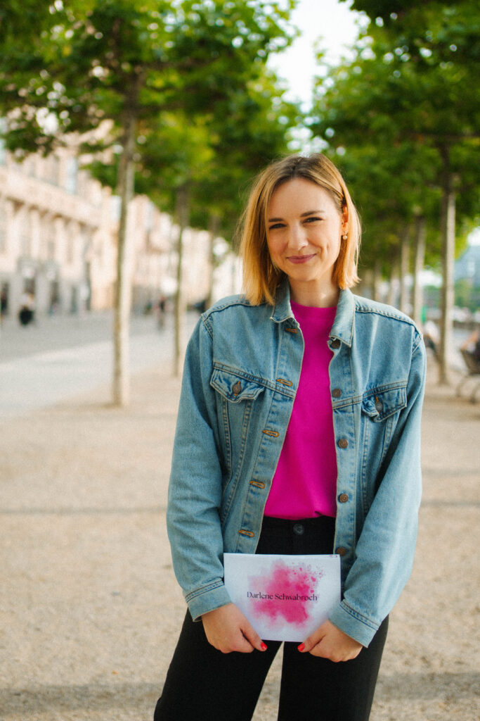 Moderatorin mit Moderationskarten auf Allee lächelt in die Kamera