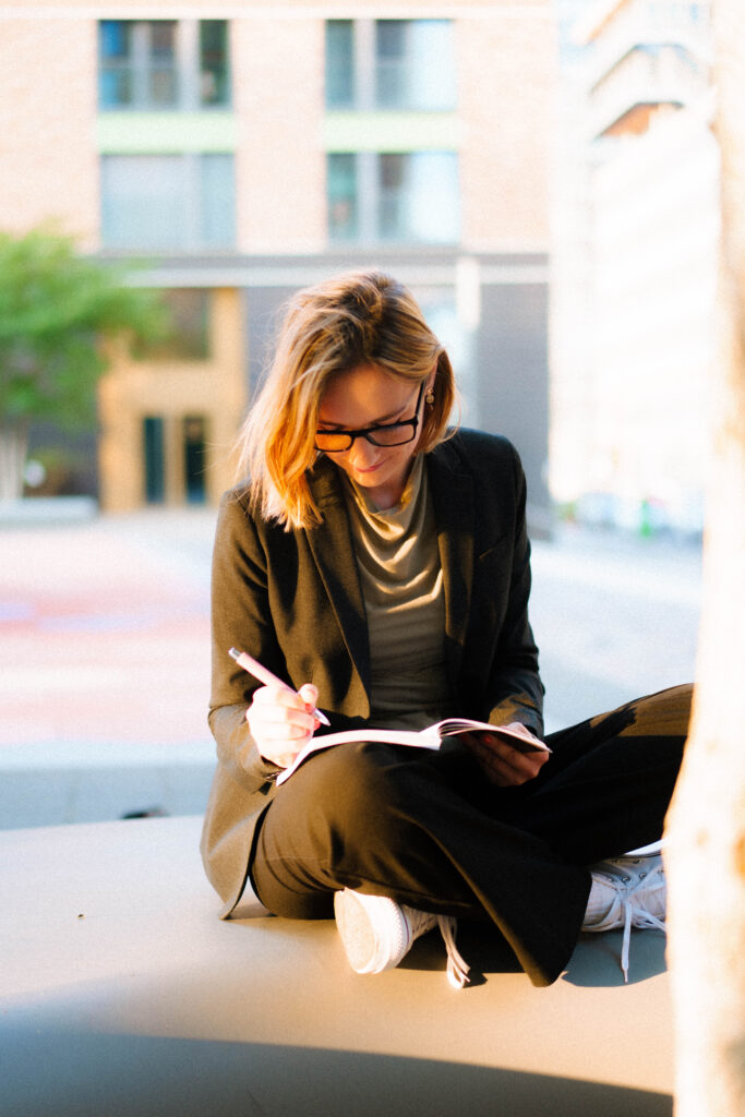 Coachin im Schneidersitz schreibt in ihr Notizbuch