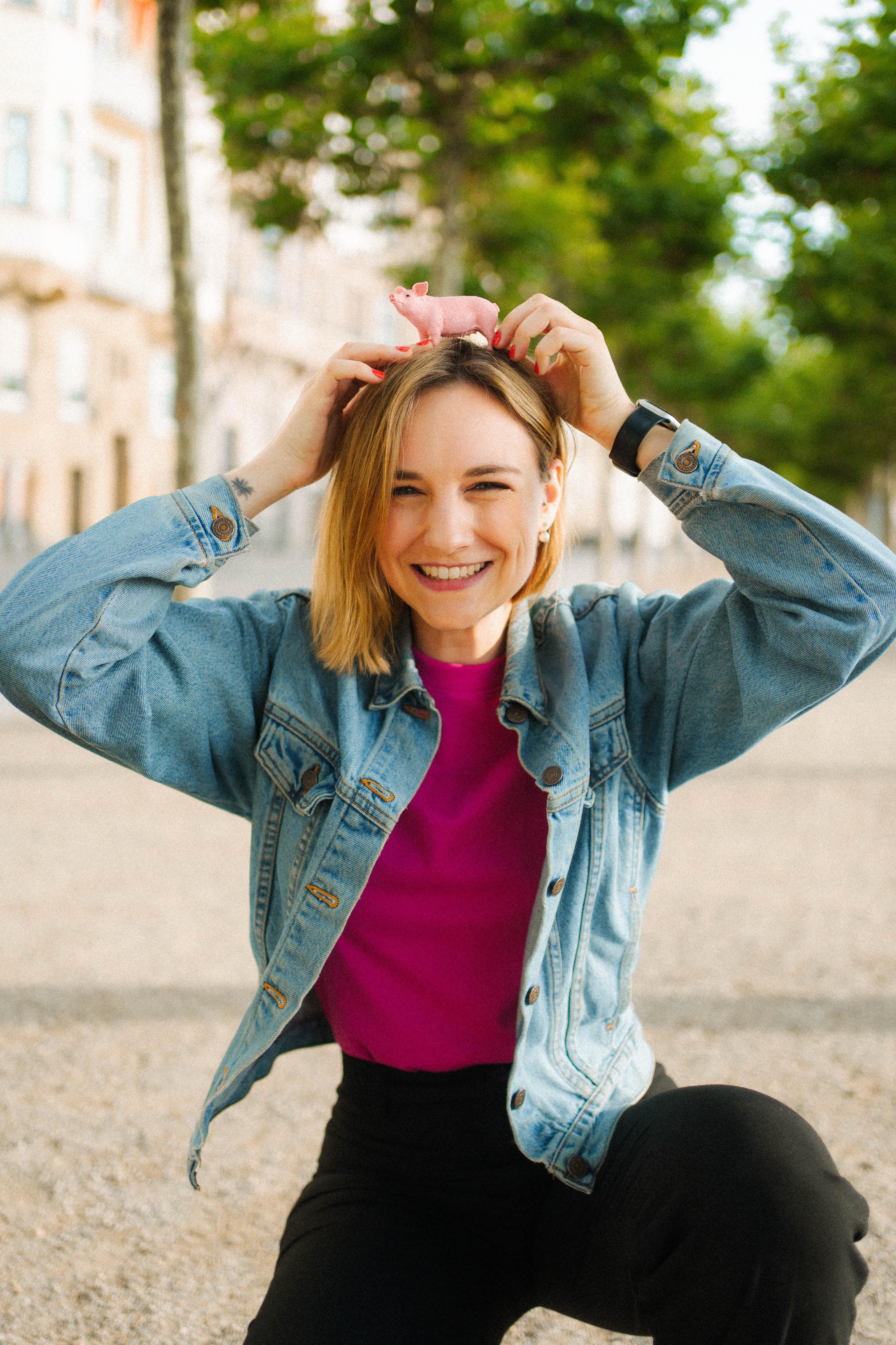 Dame hockt mit Schweinchenfigur auf dem Kopf auf dem Boden