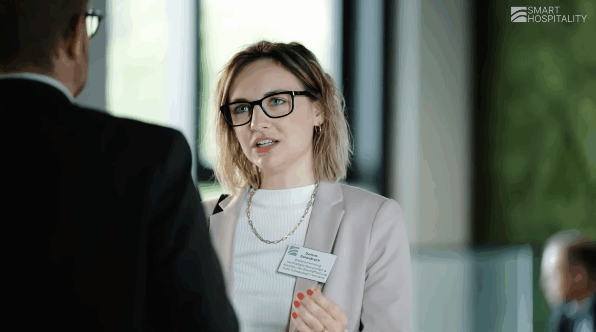 Dame mit Brille und Blazer unterhält sich